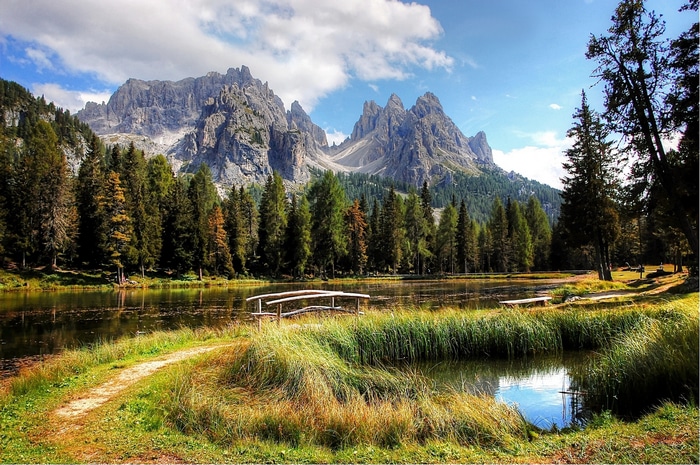 Mountains reflected in a lake with a forest and a path