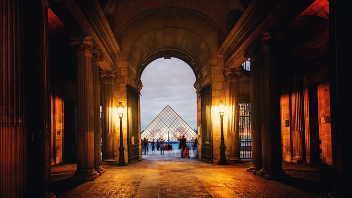 Louvre Pyramid seen through an archway at night