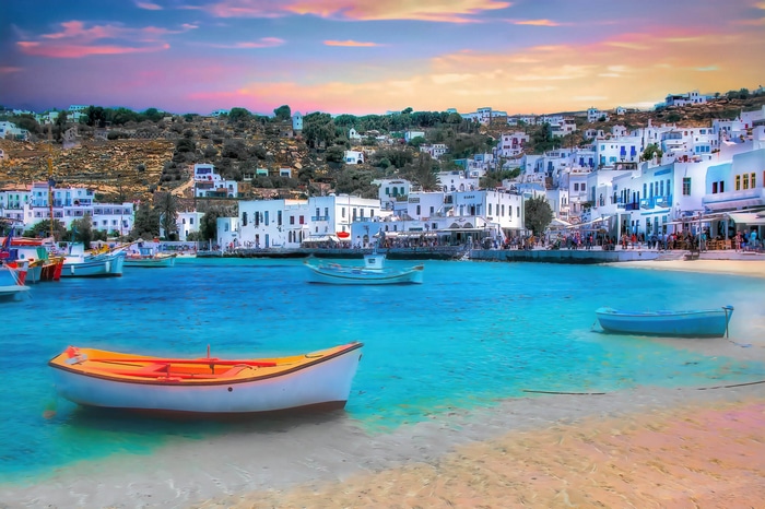 Boats in a harbor with a village at sunset