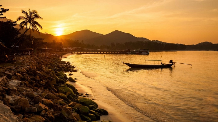 Boat on the water at sunset with rocky beach