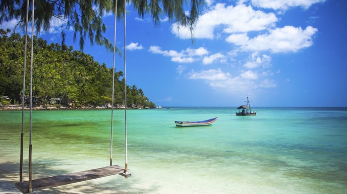 Tropical beach with swing and boats