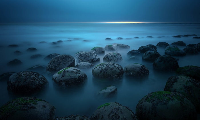Rocks in the ocean with mist at dusk