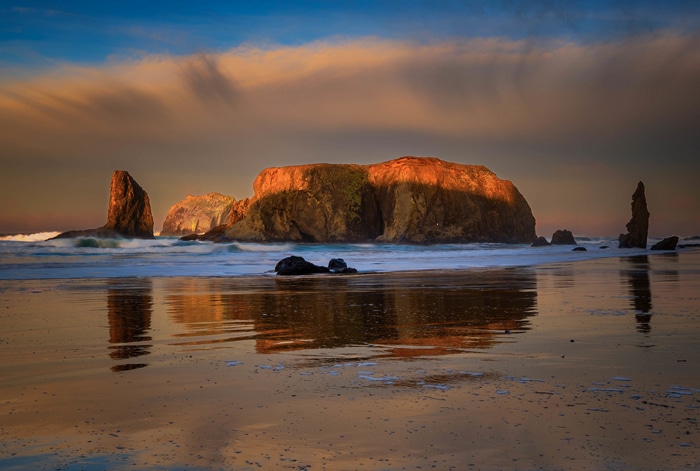 Ocean rocks and clouds at sunset with reflection