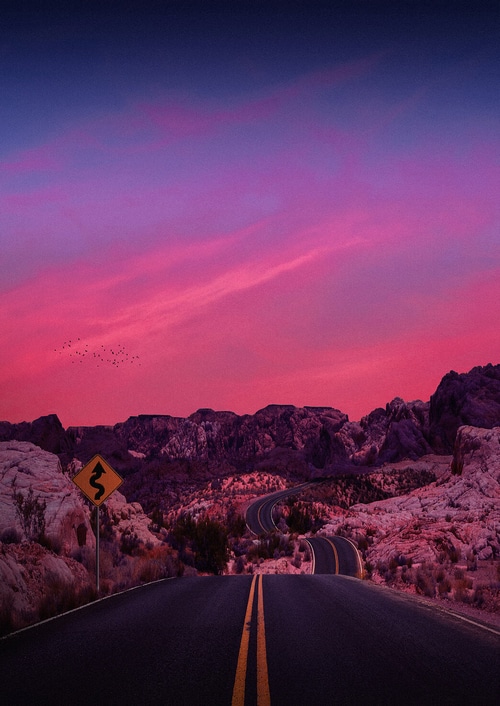 Winding desert road at sunset with mountains