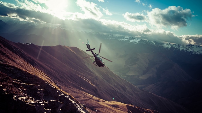 Helicopter flying over mountains with sunlight