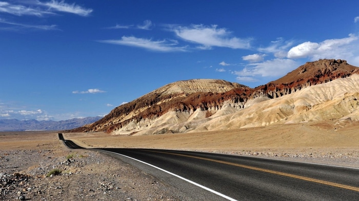 Road through colorful mountains under a blue sky