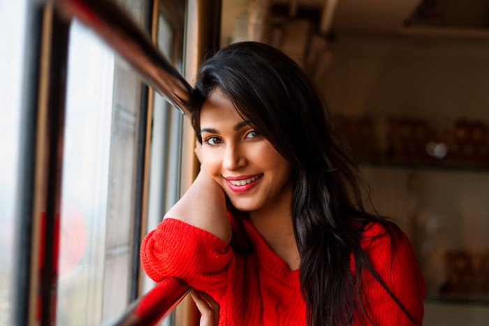 Woman with black hair smiling by the window