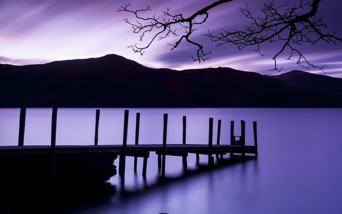 Purple lake with mountains and a wooden pier