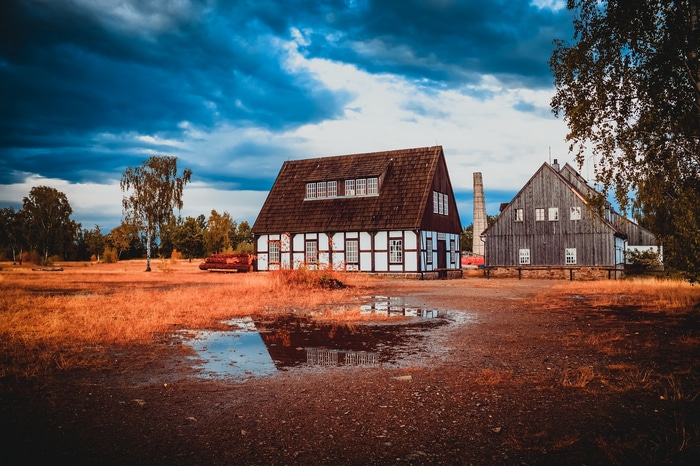 Two old houses and a chimney under a cloudy sky