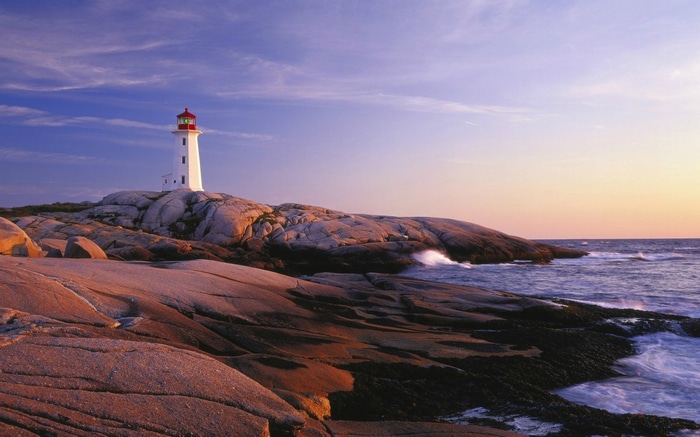 Peggy's Cove Lighthouse on rocky coast at sunset