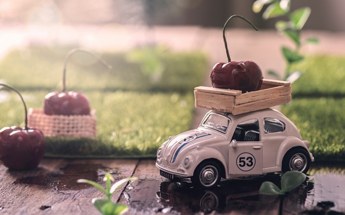 White Volkswagen Beetle toy car with cherries