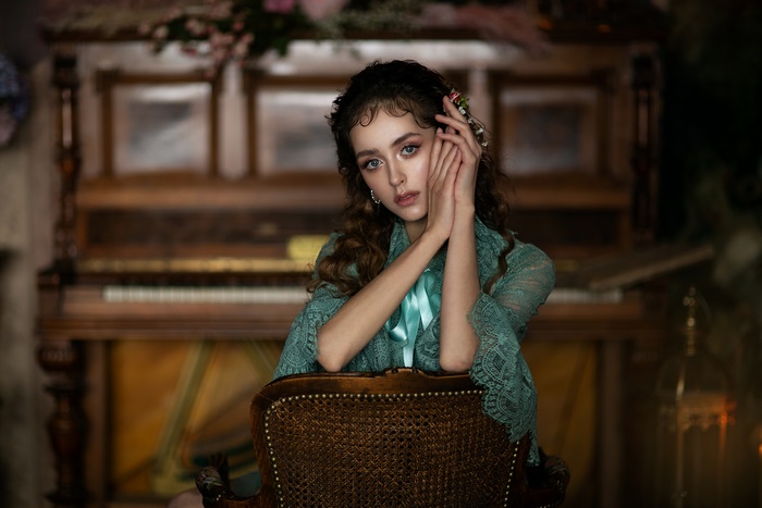 Woman with curly hair in a teal lace jacket