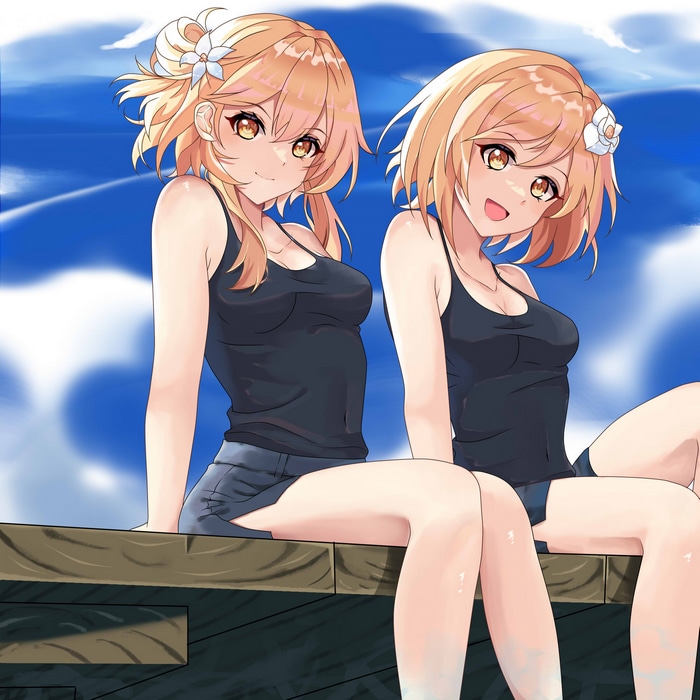 Two blonde girls in tank tops and shorts sitting outdoors