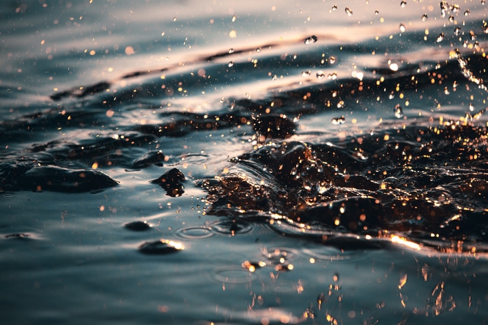 Water drops splashing in water with golden light
