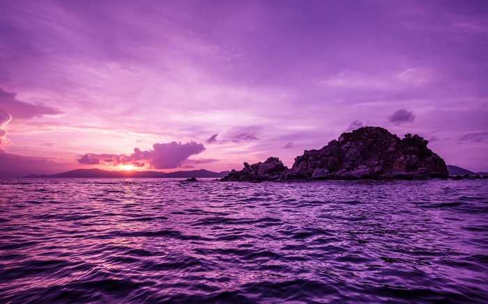 Purple sunset over the ocean with rocky island