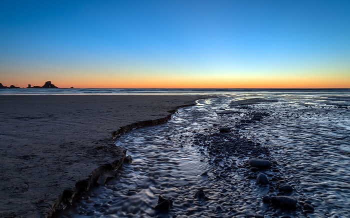 4K sunset glow over a beach with a stream