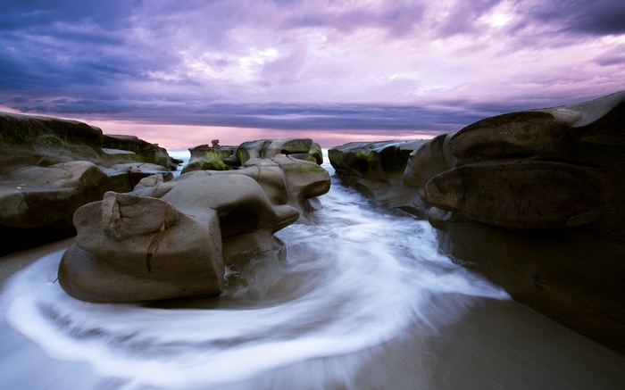 4K Purple Clouds Over Rocky Shoreline with Water