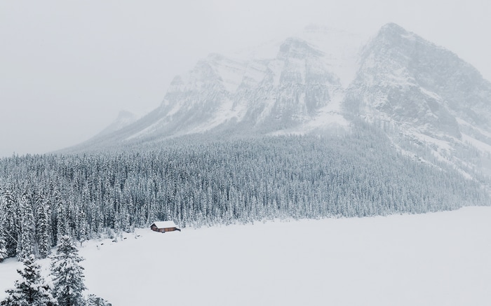 Winter landscape with snow-covered mountains and a cabin
