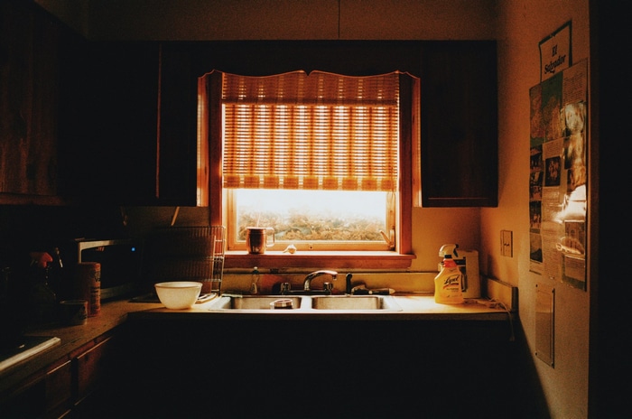Kitchen sink and window with blinds at sunset