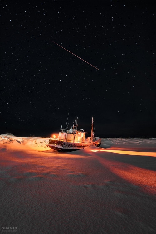 Shipwreck under the stars with a meteor shower