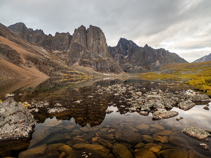 Rocky mountain lake with reflections under cloudy sky