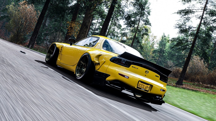 Yellow Mazda RX-7 driving on a forest road