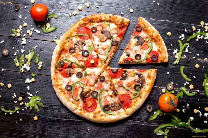 Pepperoni and mushroom pizza with vegetables on a wooden surface
