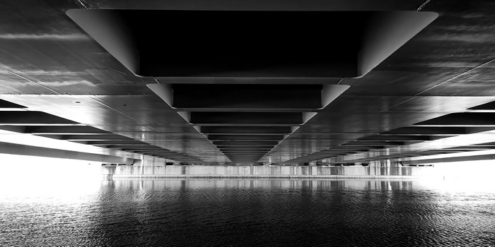 Monochrome view of bridge underside over river