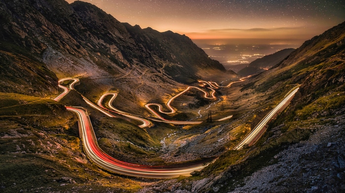 Winding mountain road with light trails at night