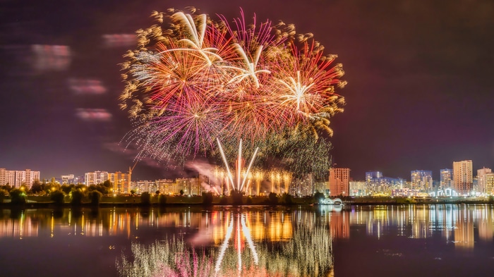Fireworks over a city reflected in water at night