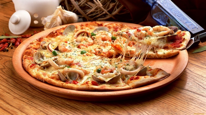 Seafood pizza with melted cheese on a wooden table