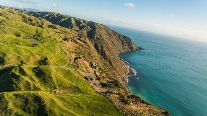 Wind turbines on rolling green hills by the sea in New Zealand
