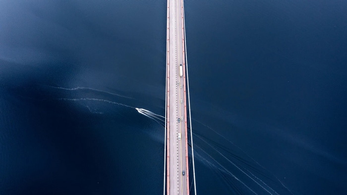 Aerial view of a bridge over a dark blue body of water with a boat