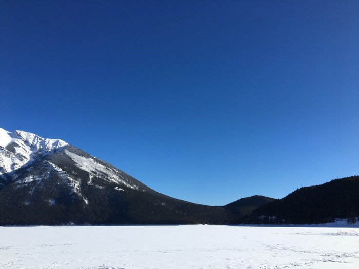 Snowy mountains and frozen lake under a clear blue sky