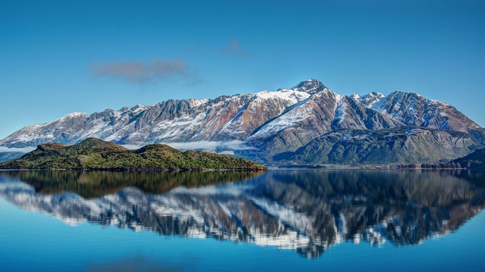 Snow-capped mountains reflecting in clear water in New Zealand