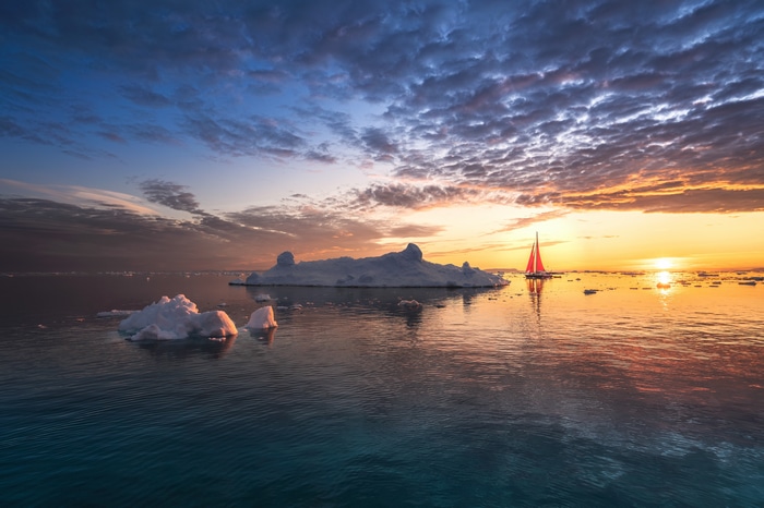 Sailboat near icebergs at sunset
