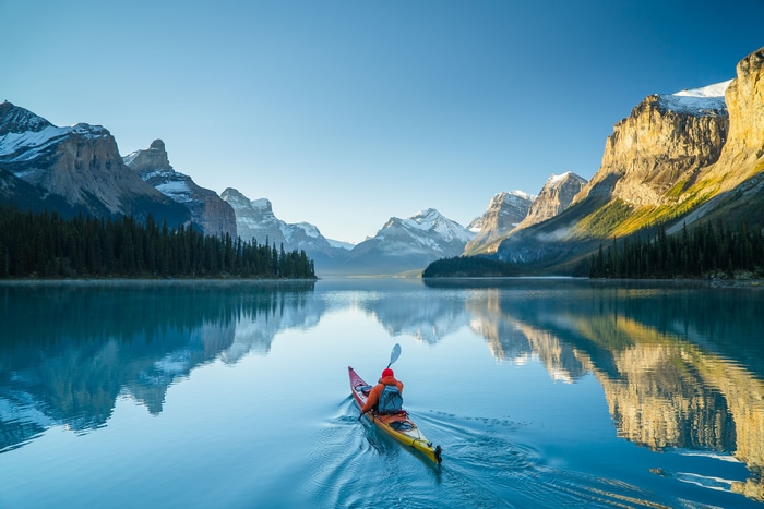 Kayaker on a calm lake with snow-capped mountains
