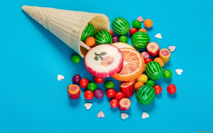 Ice cream cone spilling colorful candies and lollipops
