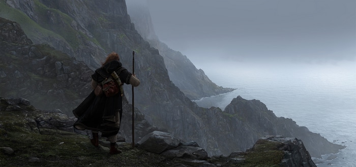 4K: Man with staff on rocky cliff overlooking sea