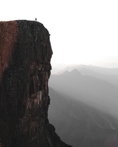 Man standing on a cliff overlooking mountains