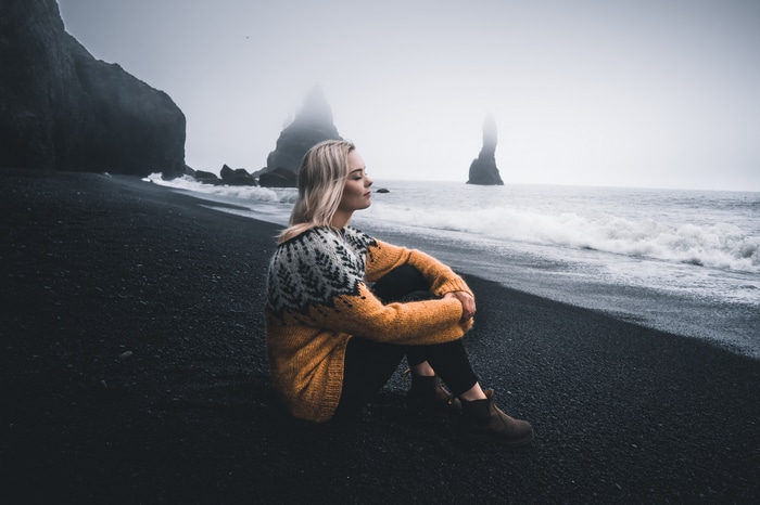 Woman in sweater on black sand beach in Iceland