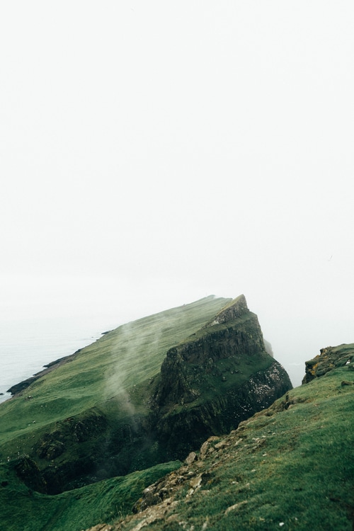 Green cliff coast with mist and water