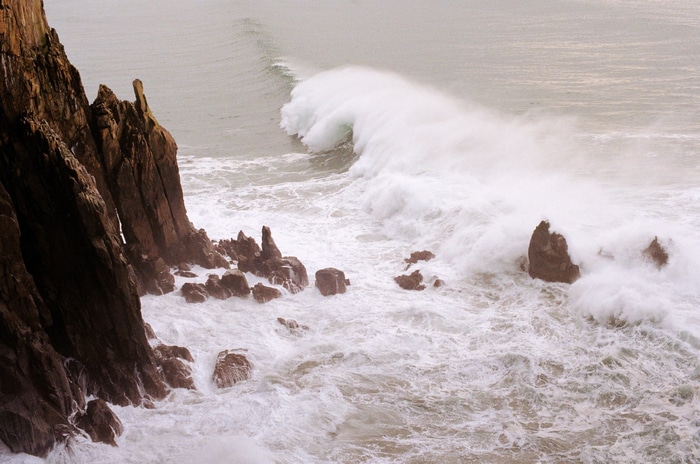 Crashing waves against rocky cliffs on a cloudy day