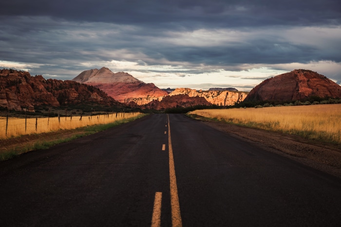 Road through rocky mountains under cloudy sky