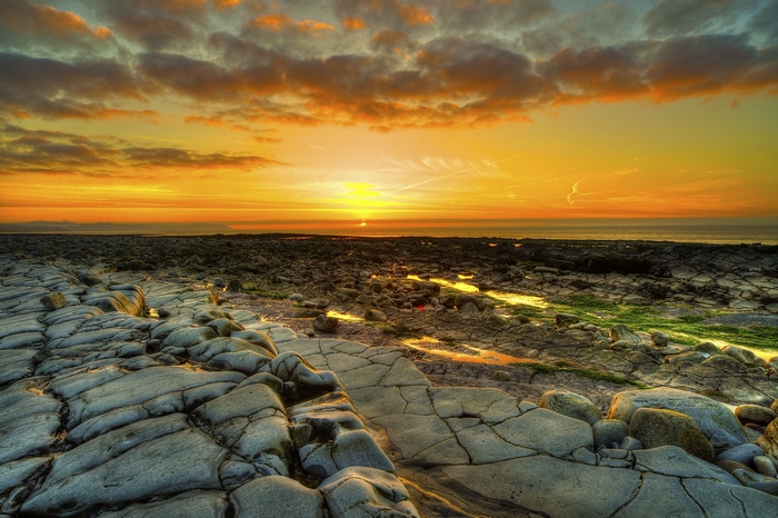 4K sunset over rocky coastline with orange clouds