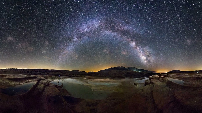Milky Way over a rocky landscape with pools