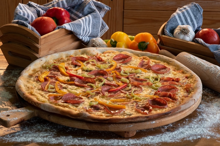 Pizza with salami and bell peppers on a cutting board