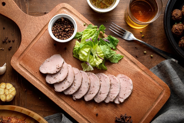 Sliced meat with salad and spices on a cutting board