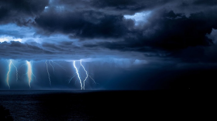 Lightning strikes over a dark ocean during a storm