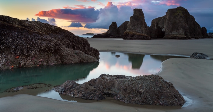 4K beach with rock formations and tide pools at sunset